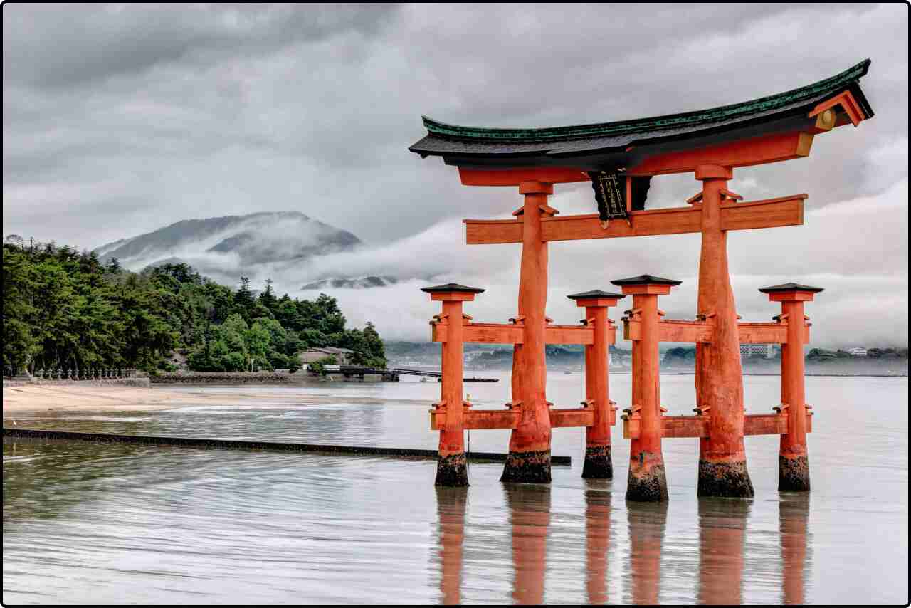 Traditional Japanese Torii gate standing at the entrance of a serene shrine in the water